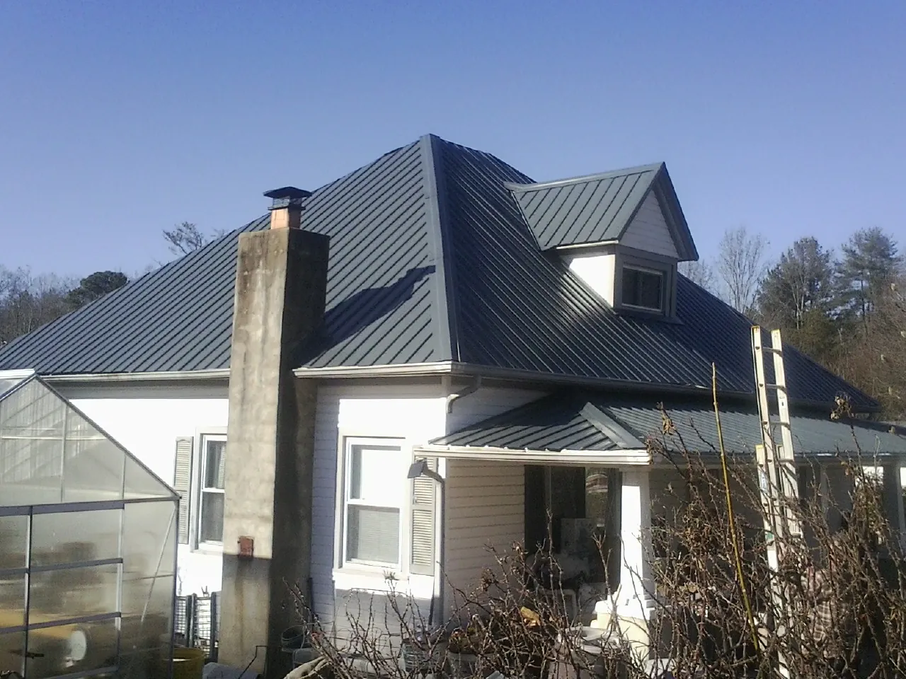 Dark blue standing seam metal roof on a white farmhouse with dormer — Slate & Tile Roof Repair by Roofing Brothers in Washington Crossing