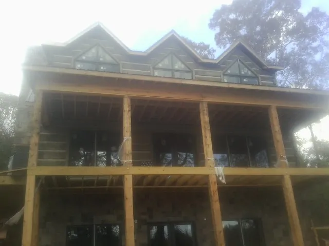 Dormers and porch framing on a large log home under construction — Roof Coating work by our crew in Washington Crossing