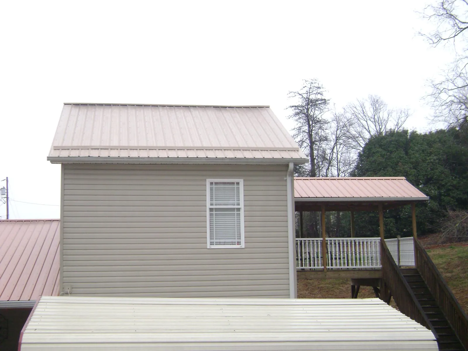 Tan metal roofs on a two story addition and attached porch, from a Roof Replacement job in Washington Crossing