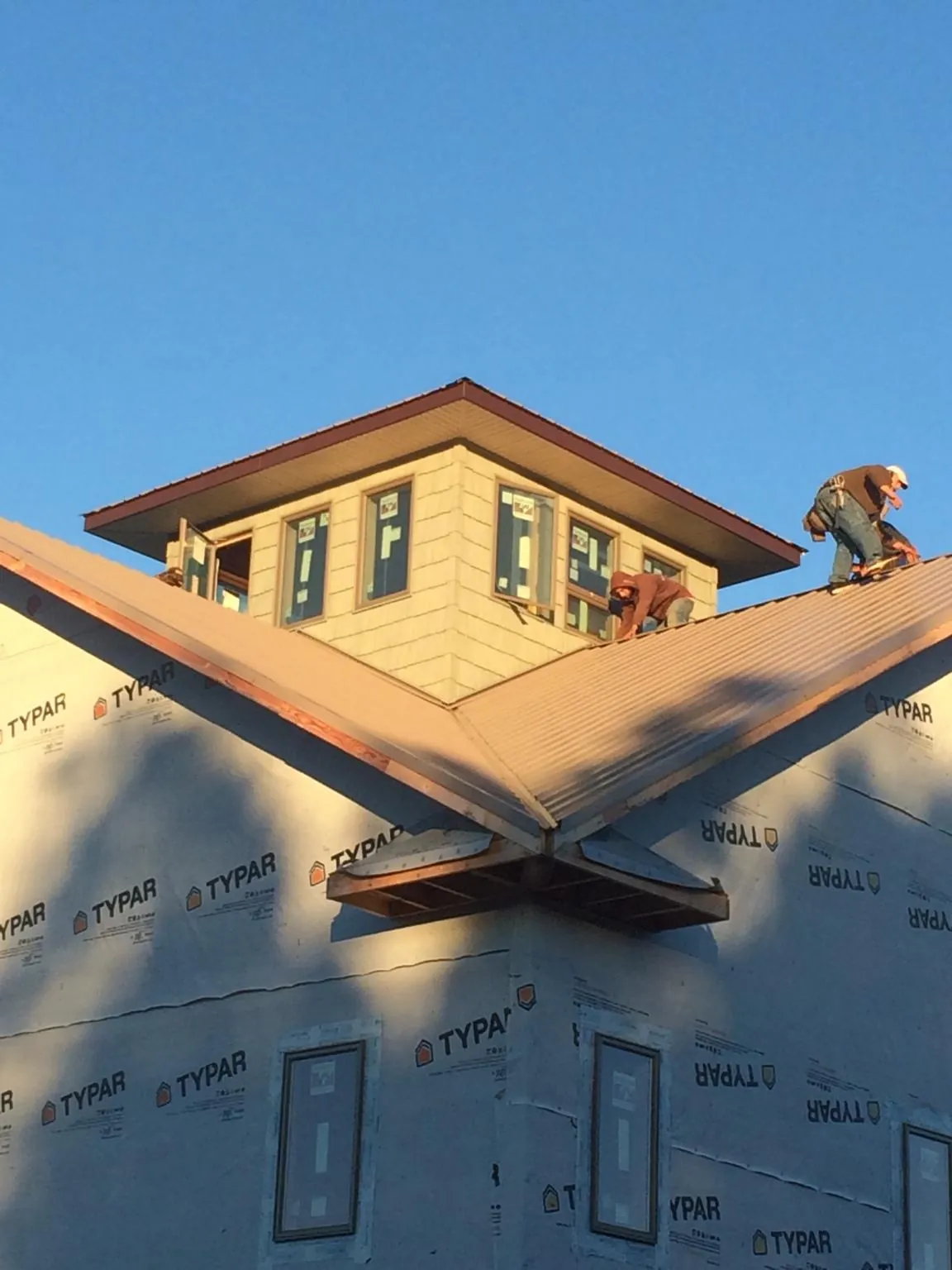Roofers working around a rooftop cupola on a new metal roof at sunset — Roof Waterproofing in Washington Crossing by Roofing Brothers